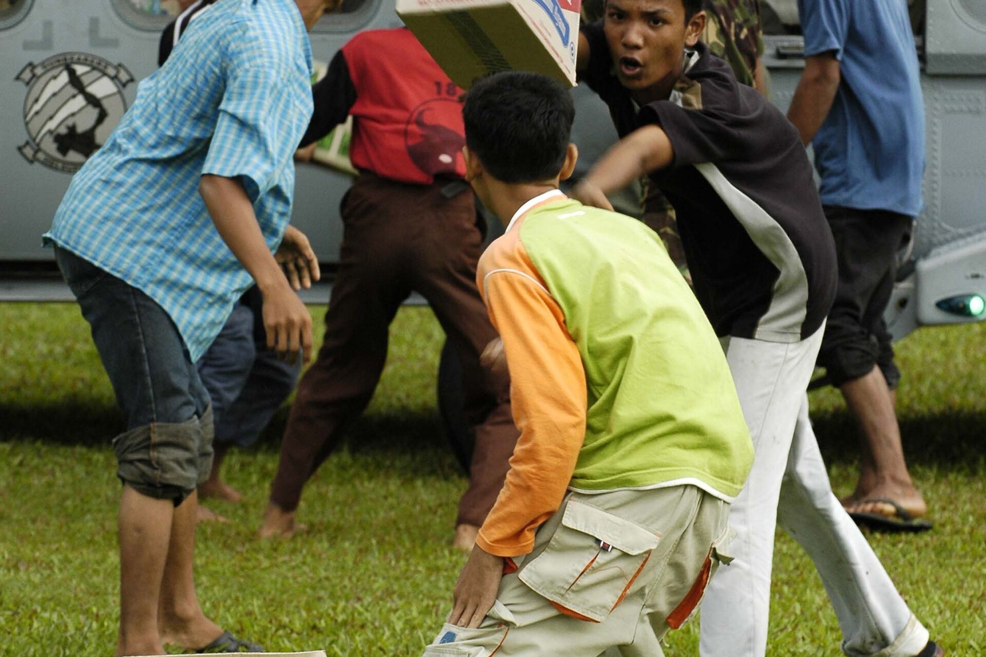 Anak-anak di Lamno, Aceh, bekerja sama membongkar bantuan kemanusiaan, Januari 2005